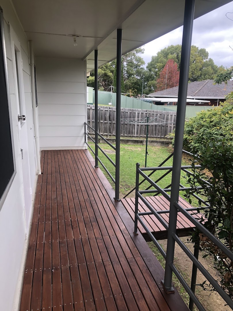 An oiled hardwood deck running along the side of a house under a covered verandah