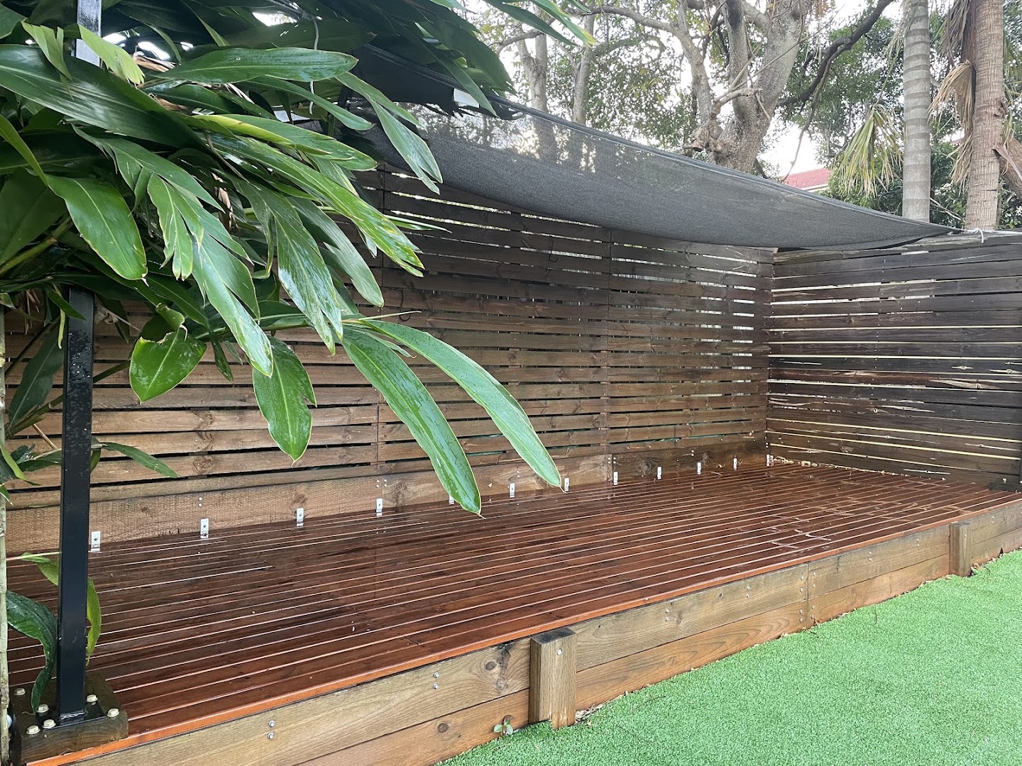A long oiled timber deck with a horizontal slatted privacy screen along one side