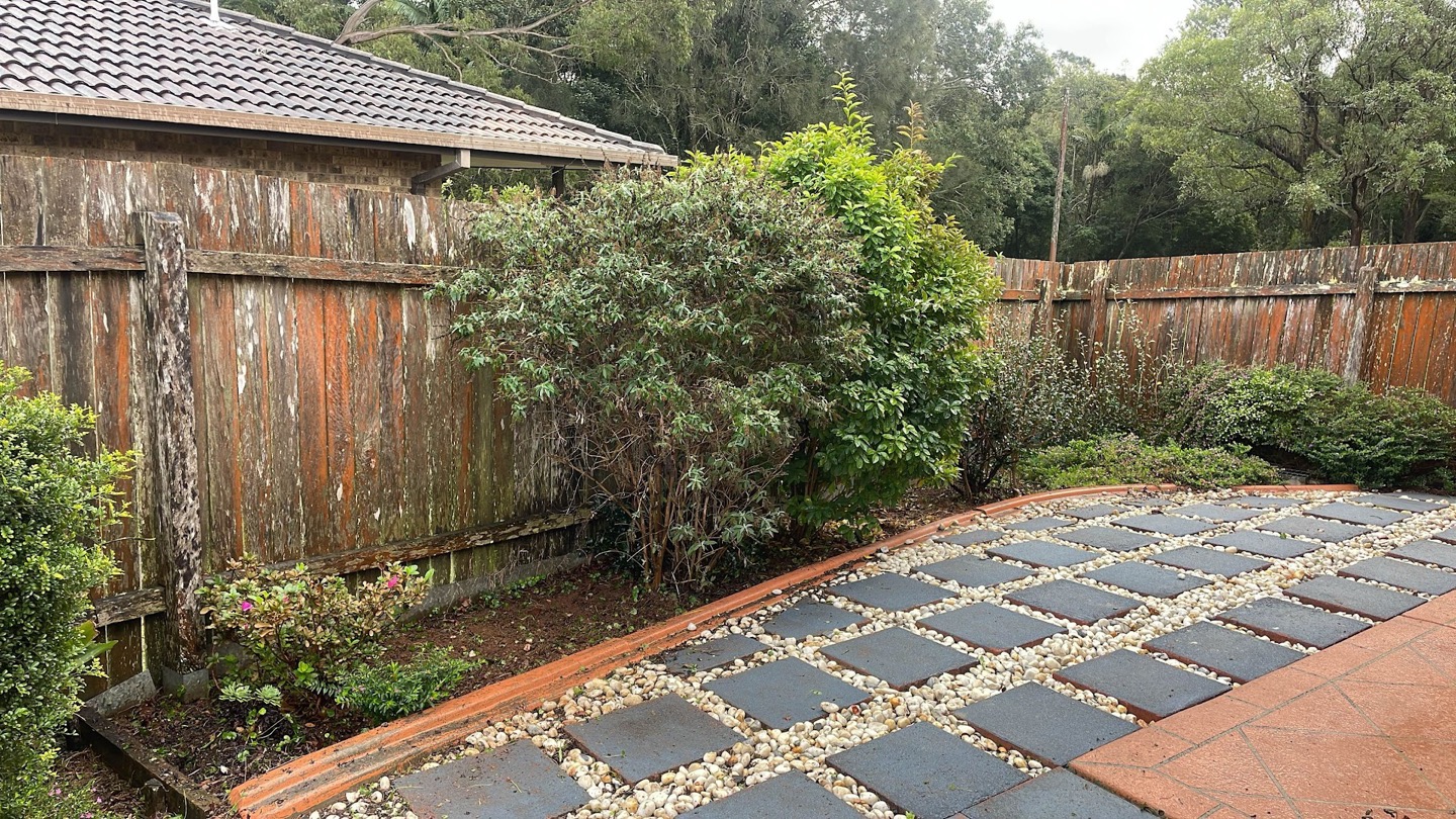 Square pavers set into gravel forming a path along a timber fence line